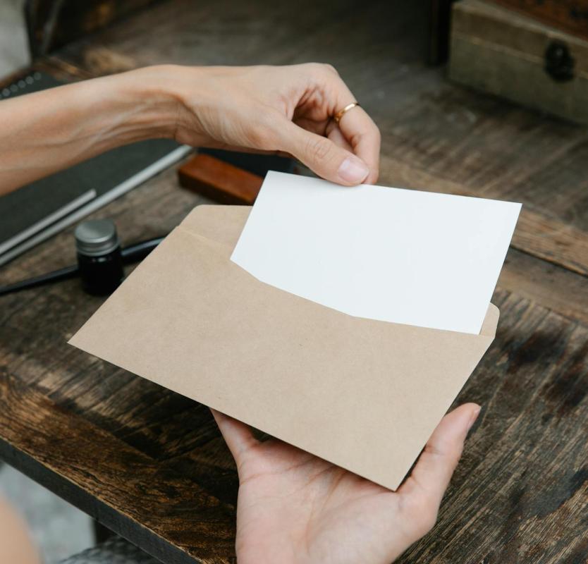Close-up of hands holding an envelope with a letter on a rustic wooden desk, ideal for communication themes.