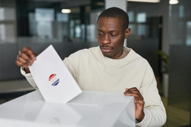 A man casts his vote in an office environment, focused and serious.