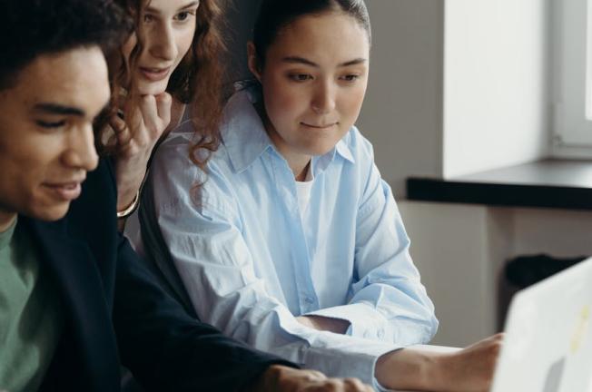 A diverse team of professionals collaborating on a laptop in an office setting.